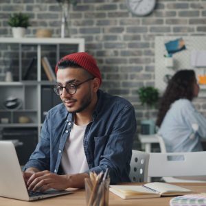 Multiethnic team working on laptops and projects in a modern and creative co-working office space.